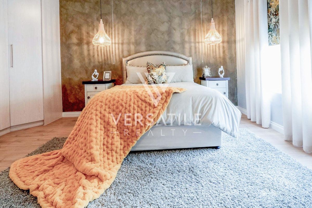 A well-maintained bedroom featuring laminate flooring, built-in wardrobes, and decorative pendant lighting against a textured feature wall.
