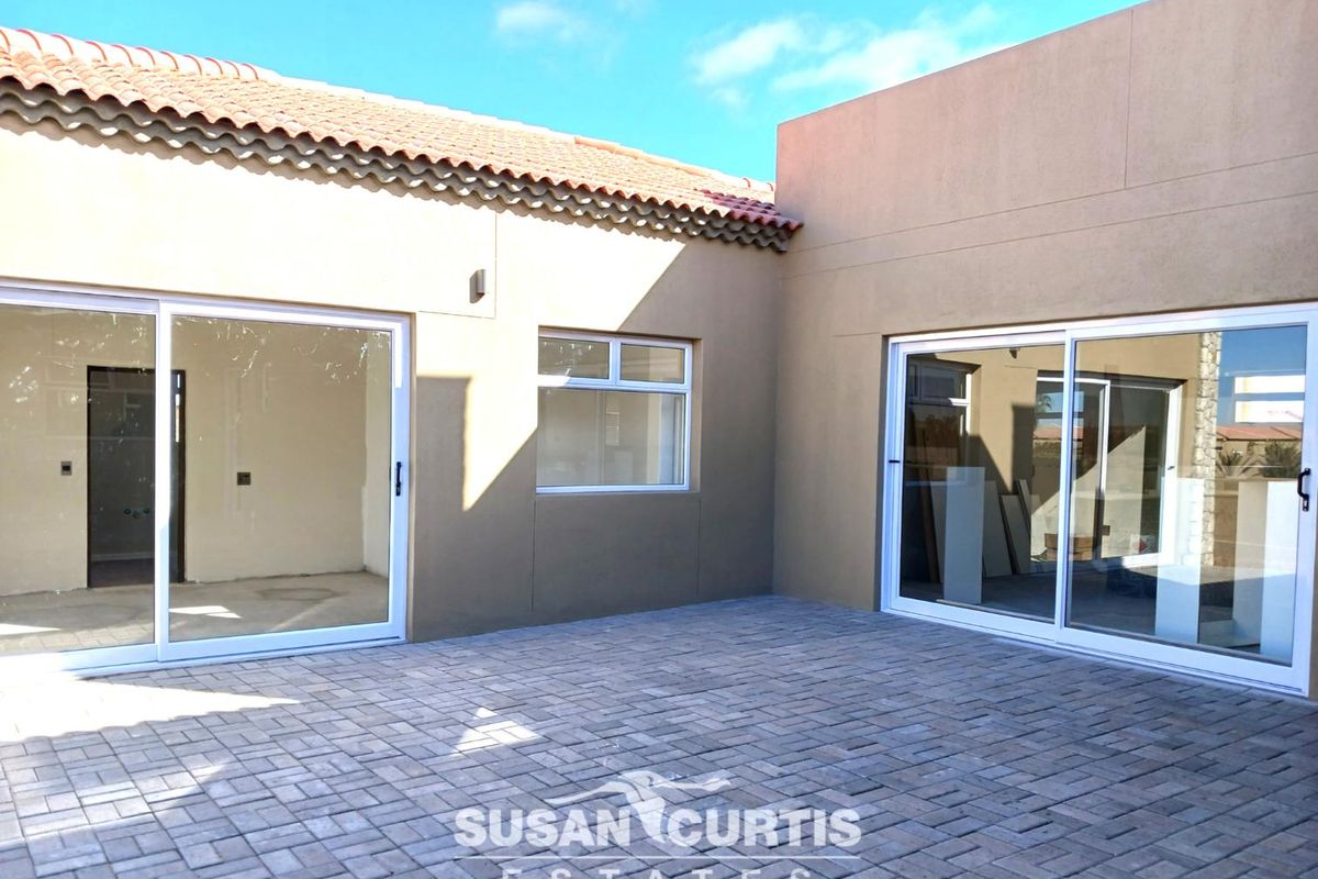 A clean, paved rear patio area featuring modern sliding glass doors providing access to the interior living spaces.