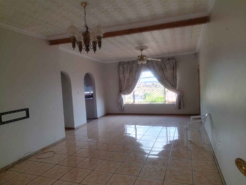 Spacious living area featuring tiled flooring, arched architectural details, and a ceiling fan, offering a bright and open layout.