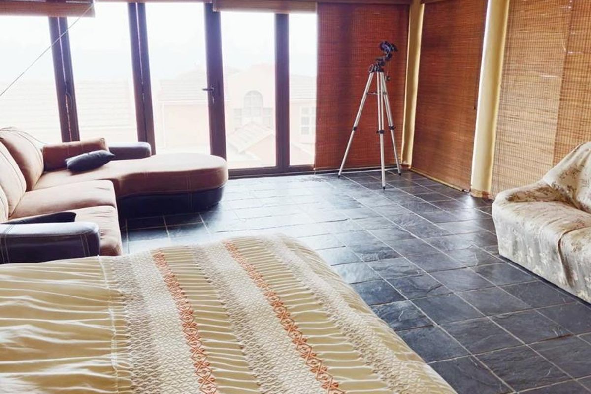 Spacious bedroom featuring dark slate tile flooring, large windows with bamboo blinds, and recessed ceiling lighting.