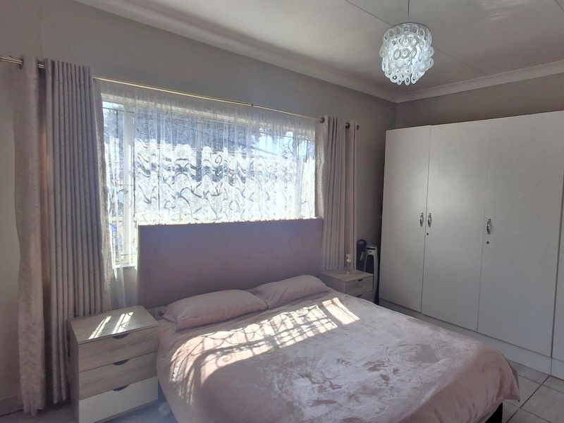 A well-maintained bedroom featuring built-in wardrobes, tiled flooring, and neutral wall finishes, offering a clean and functional living space.