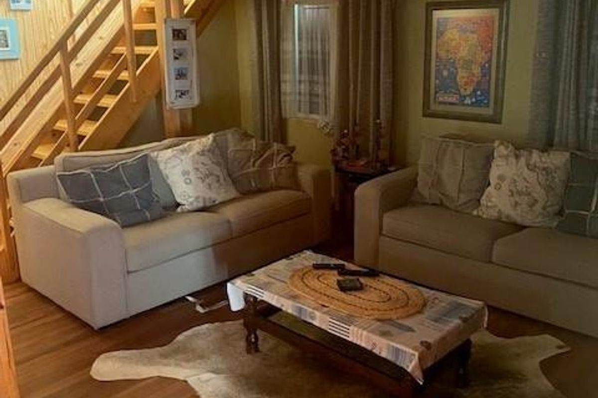 A cozy living room featuring warm timber flooring and a wooden staircase, creating a rustic and inviting atmosphere.