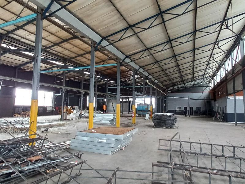 Large open-plan industrial warehouse space featuring a steel portal frame structure, concrete flooring, and high-bay lighting, suitable for manufacturing or storage operations.