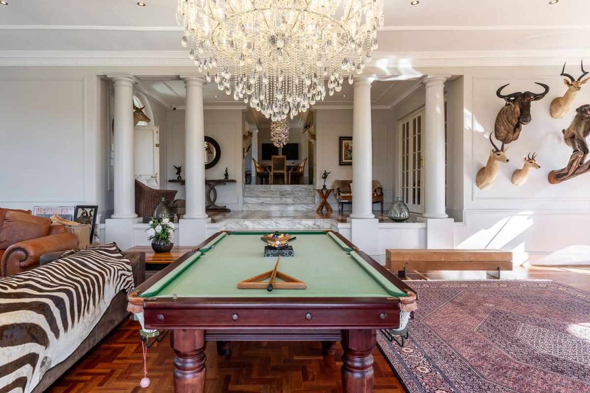 Elegant living area featuring rich parquet flooring, classical columns, marble steps, and a grand crystal chandelier, creating a sophisticated and spacious atmosphere.
