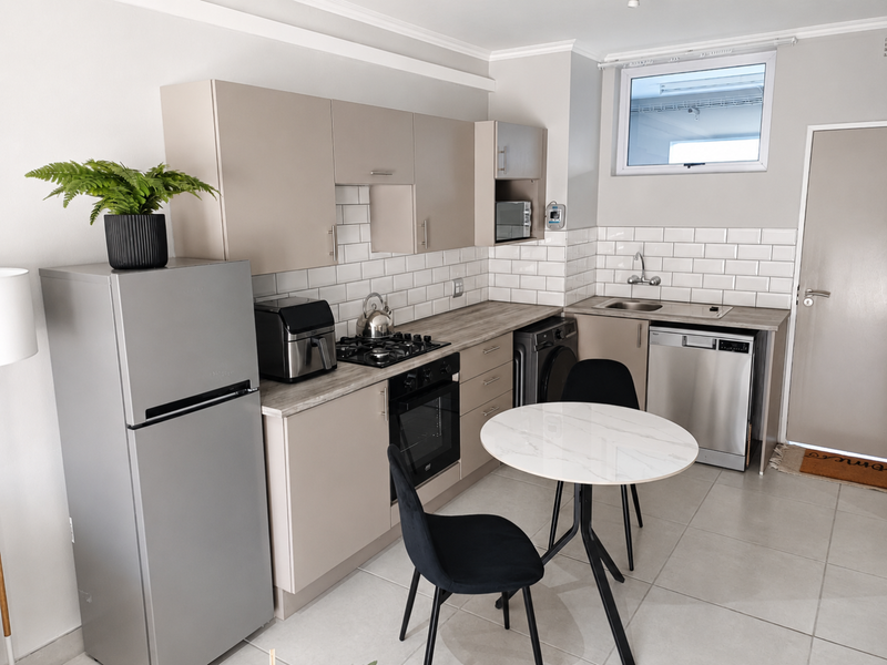 A modern, well-maintained kitchen featuring neutral cabinetry, subway tile backsplash, integrated appliances, and tiled flooring, offering a clean and functional cooking space.