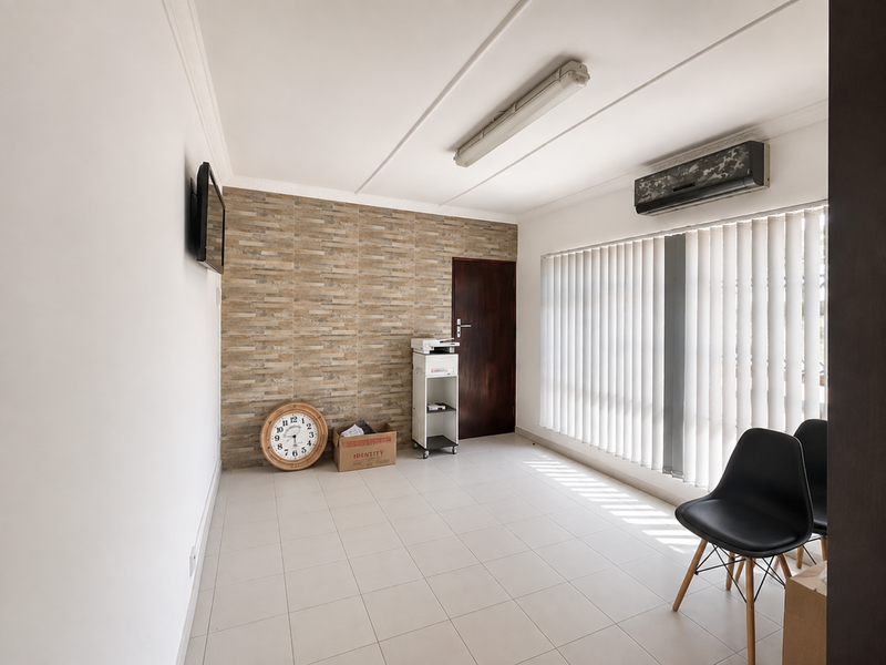 A bright, tiled living area featuring a stone-cladding accent wall, vertical blinds, and a wall-mounted air conditioning unit.