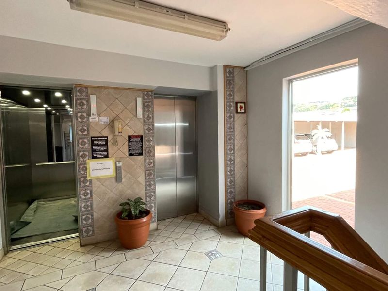Apartment building entrance lobby featuring an elevator, tiled flooring, and access to the staircase.