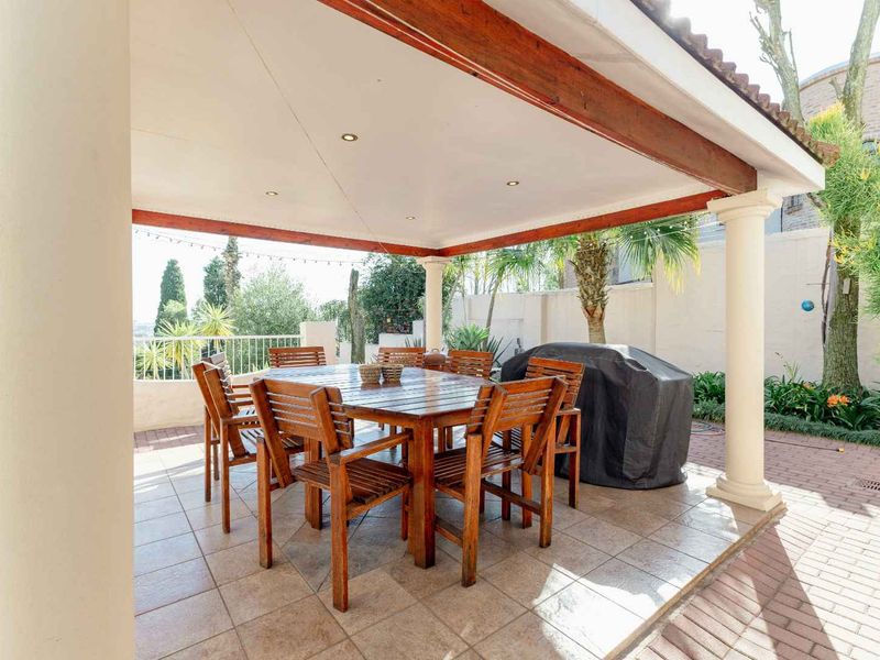 A spacious covered patio featuring tiled flooring, recessed lighting, and support columns, providing an ideal outdoor area for dining and entertaining.