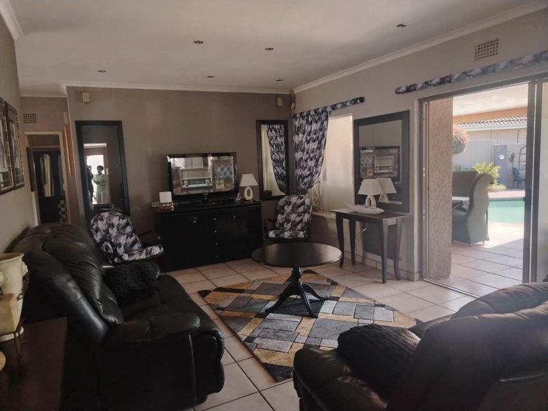 Spacious living room featuring tiled flooring, recessed lighting, and large sliding glass doors providing direct access to the outdoor patio and pool area.
