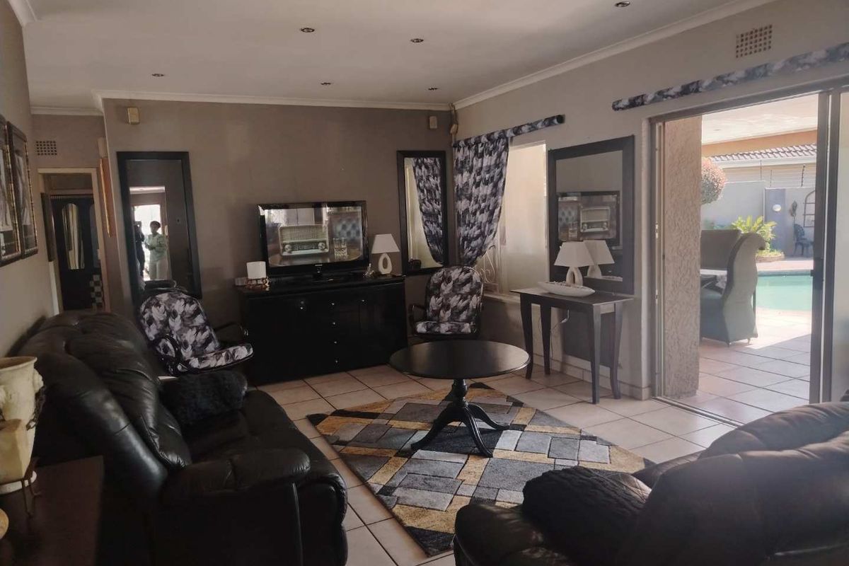 Spacious living room featuring tiled flooring, recessed lighting, and large sliding glass doors providing direct access to the outdoor patio and pool area.