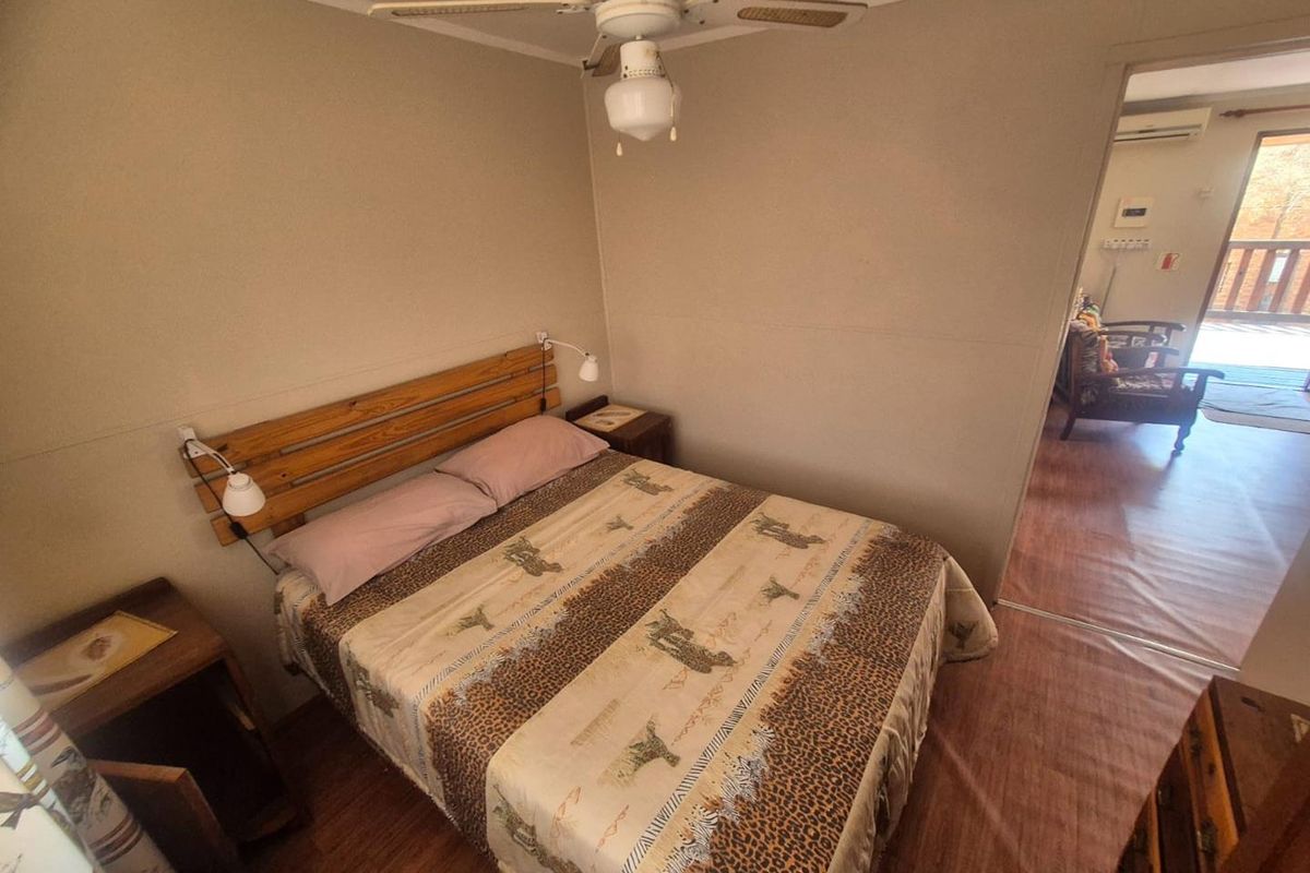 A functional bedroom featuring wood-look flooring, a ceiling fan, and direct access to an adjoining living area.