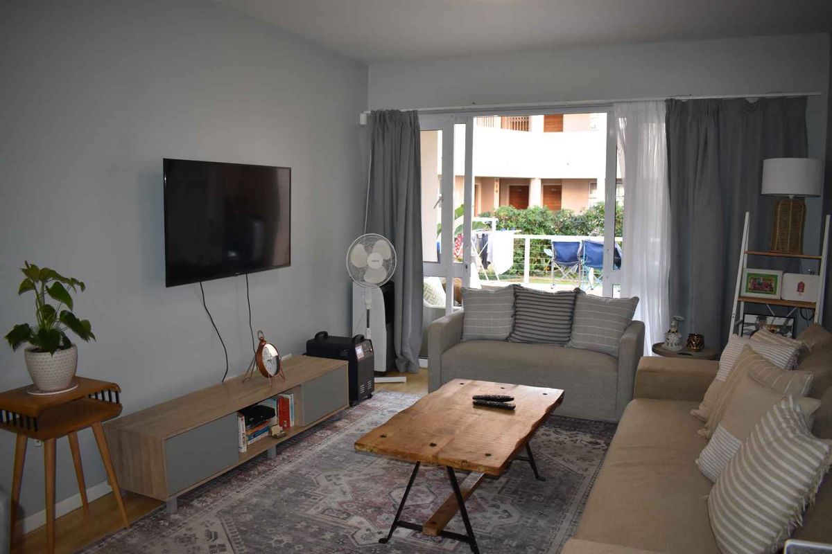 A comfortable living room featuring neutral walls, laminate flooring, and large sliding glass doors that provide access to an outdoor patio area.