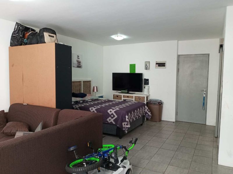 Open plan living and sleeping area featuring tiled flooring and neutral walls, offering a functional layout for an apartment setting.