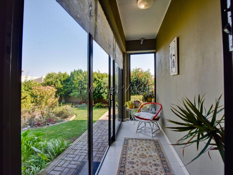 A covered patio area featuring tiled flooring and large sliding glass doors that provide direct access to the garden.