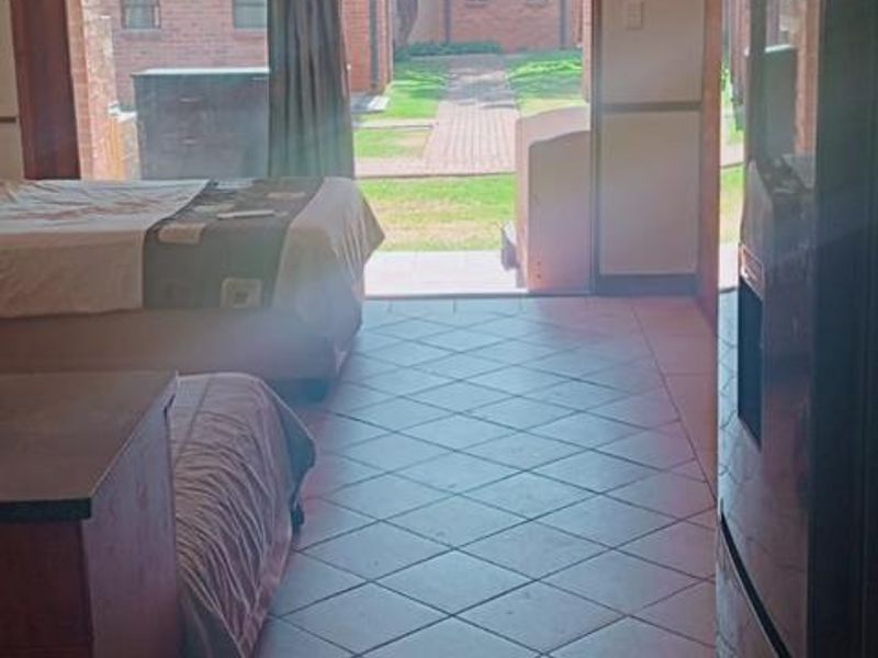Open plan living area featuring tiled flooring and a sliding glass door providing direct access to the exterior garden area.