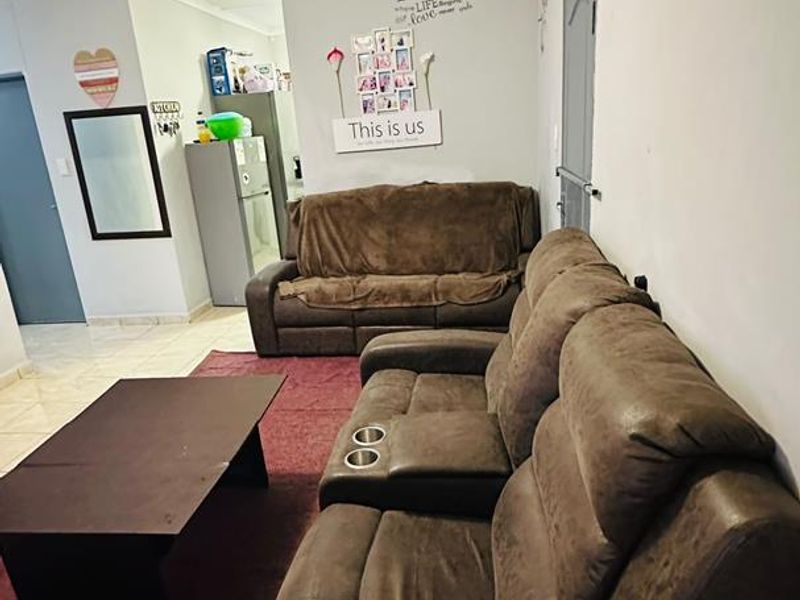 A living room area featuring tiled flooring and ceiling panels, providing a functional space with direct access to the kitchen area.