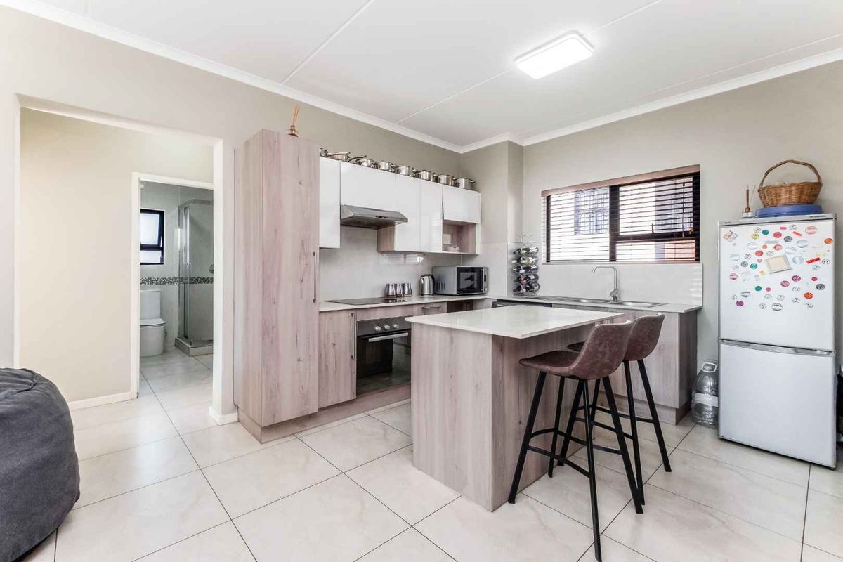 Modern kitchen featuring light wood-grain cabinetry, stone-look countertops, a central breakfast island, and integrated stainless steel oven and extractor fan.