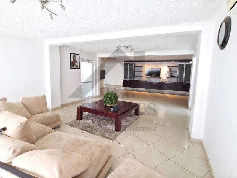 Spacious living area featuring tiled flooring, built-in cabinetry, and a split-system air conditioner, offering a versatile layout for comfortable family living.