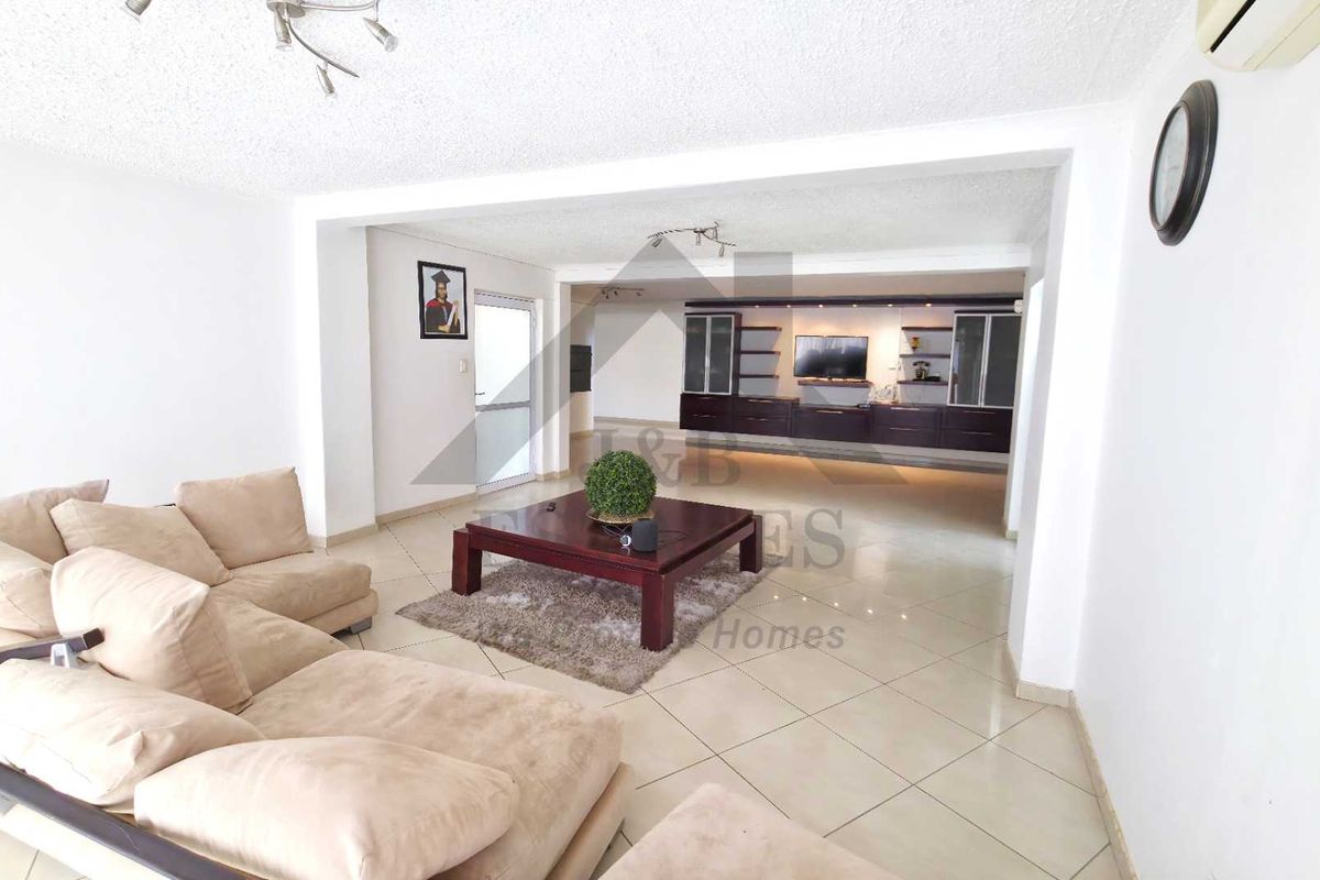 Spacious living area featuring tiled flooring, built-in cabinetry, and a split-system air conditioner, offering a versatile layout for comfortable family living.