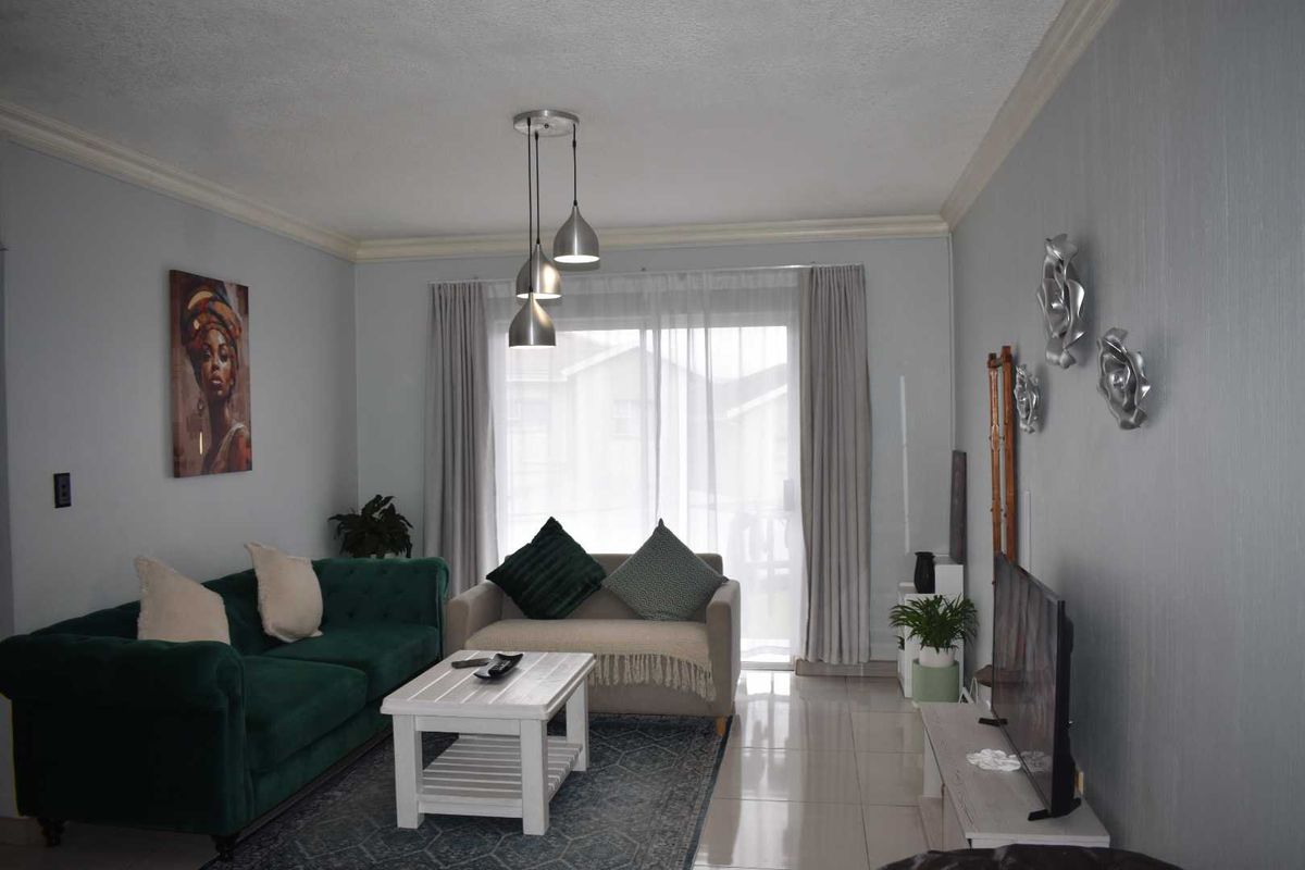 A well-lit living room featuring tiled flooring, crown molding, and a sliding glass door providing access to the exterior.