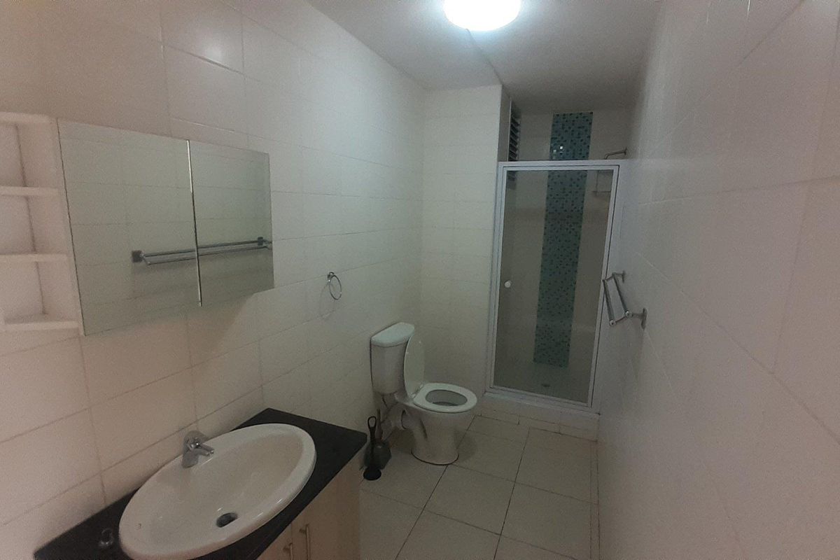 A functional bathroom featuring a vanity with a basin, a toilet, and a separate shower enclosure with tiled walls and flooring.