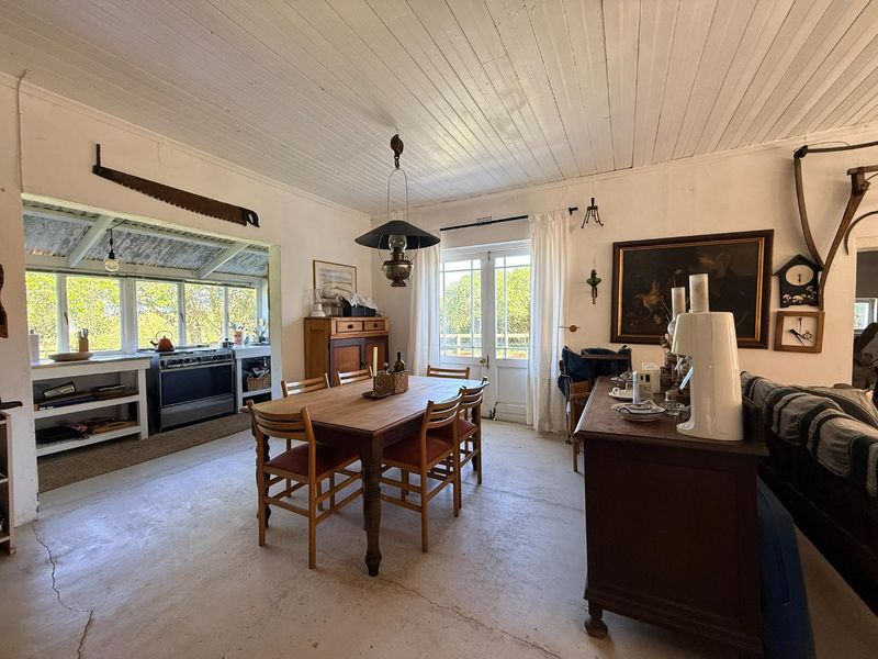 Open plan dining and kitchen area featuring rustic timber ceilings, concrete flooring, and direct access to the outdoors through french doors.