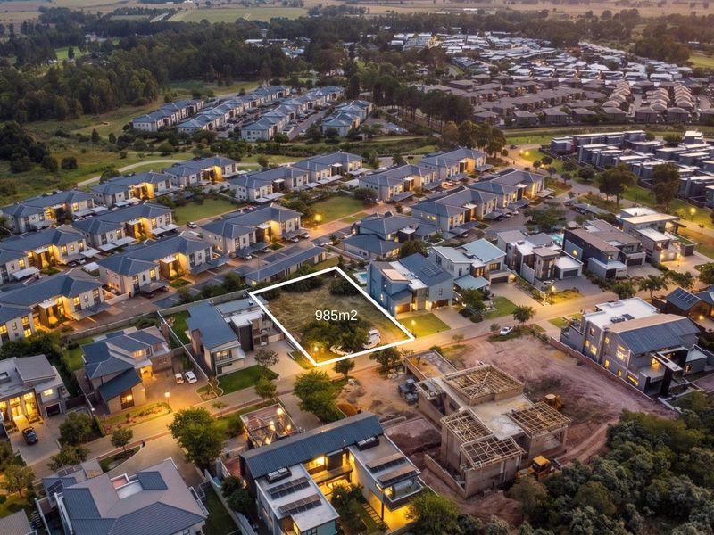 An aerial view of a 985m2 vacant residential plot situated within a developed estate, highlighting the available land and surrounding neighborhood context.