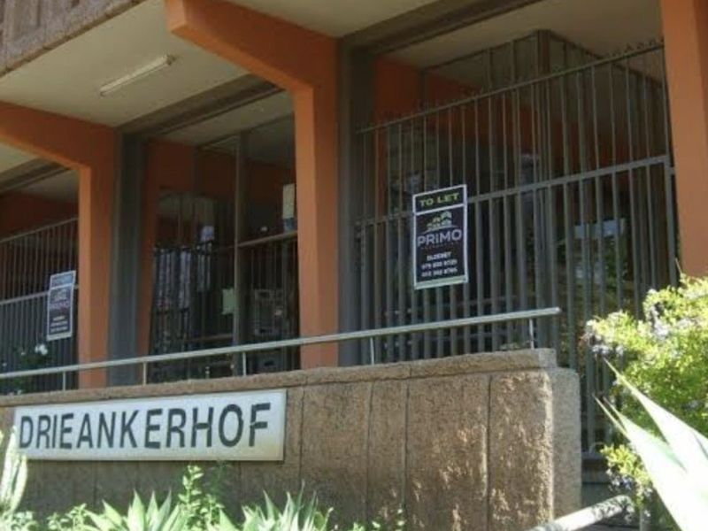 Front entrance view of the Drieankerhof apartment building featuring a secure gated access point and concrete architectural detailing.