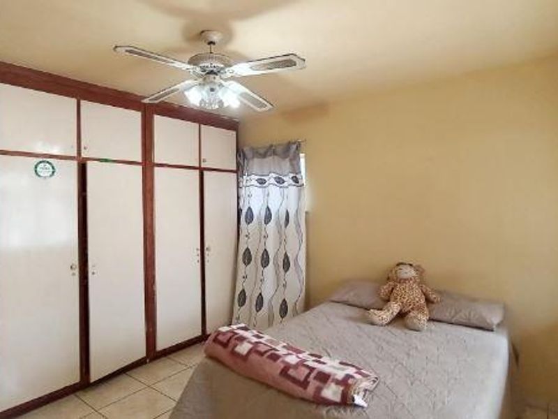 A bedroom featuring built-in cupboards, a ceiling fan, and tiled flooring.
