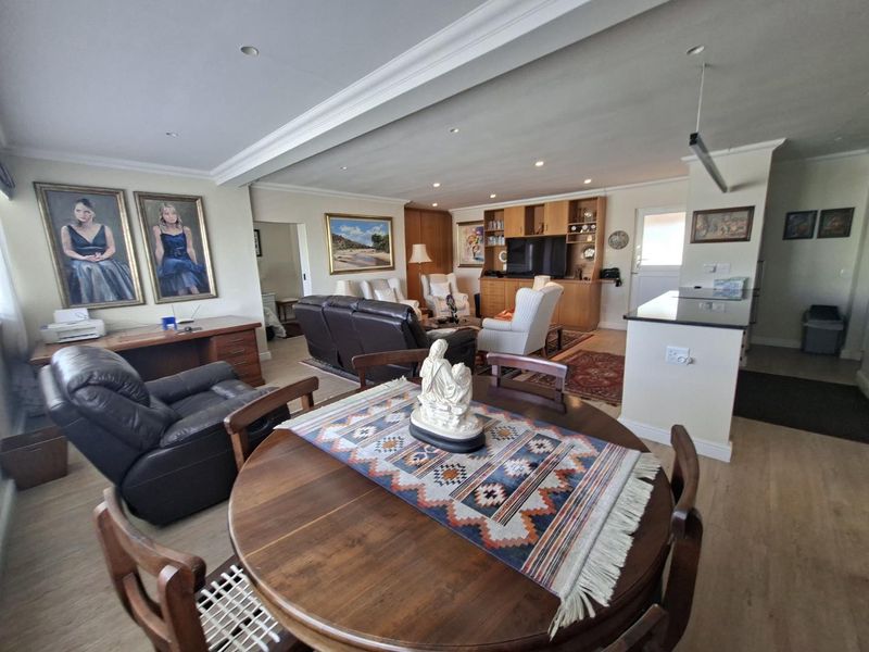 Spacious open-plan living and dining area featuring laminate flooring, recessed lighting, crown molding, and built-in cabinetry with a functional kitchen island.