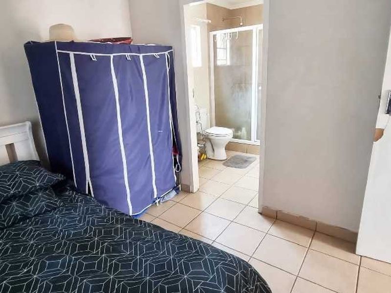 A bedroom featuring tiled flooring and an adjoining en-suite bathroom equipped with a shower and toilet.