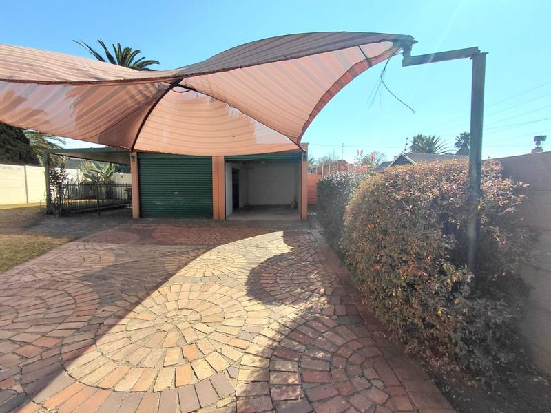 A paved driveway area featuring a shade sail structure and a garage with a roller shutter door.