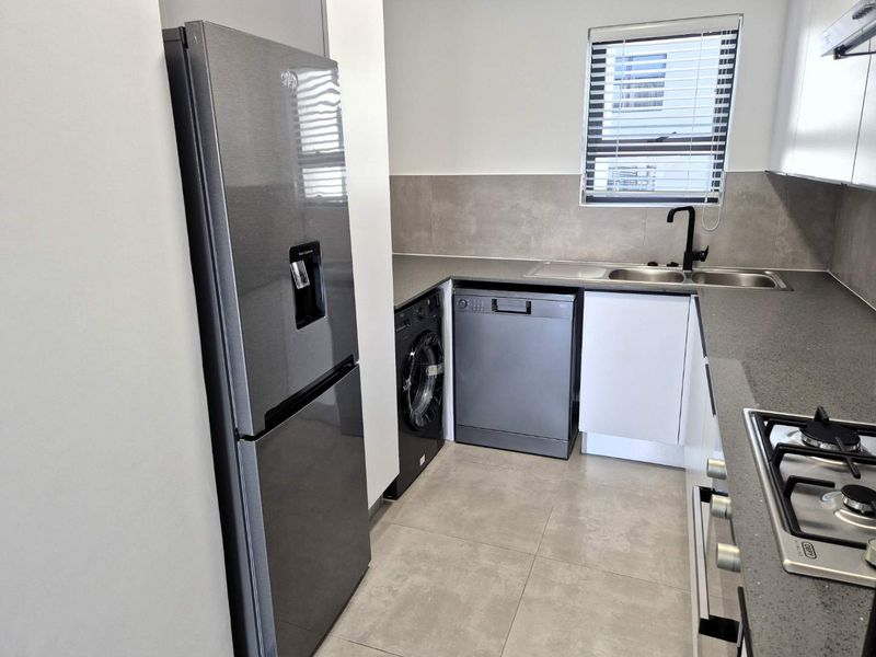Modern kitchen featuring stone countertops, built-in cabinetry, gas hob, stainless steel sink, and tiled finishes in a clean, contemporary layout.