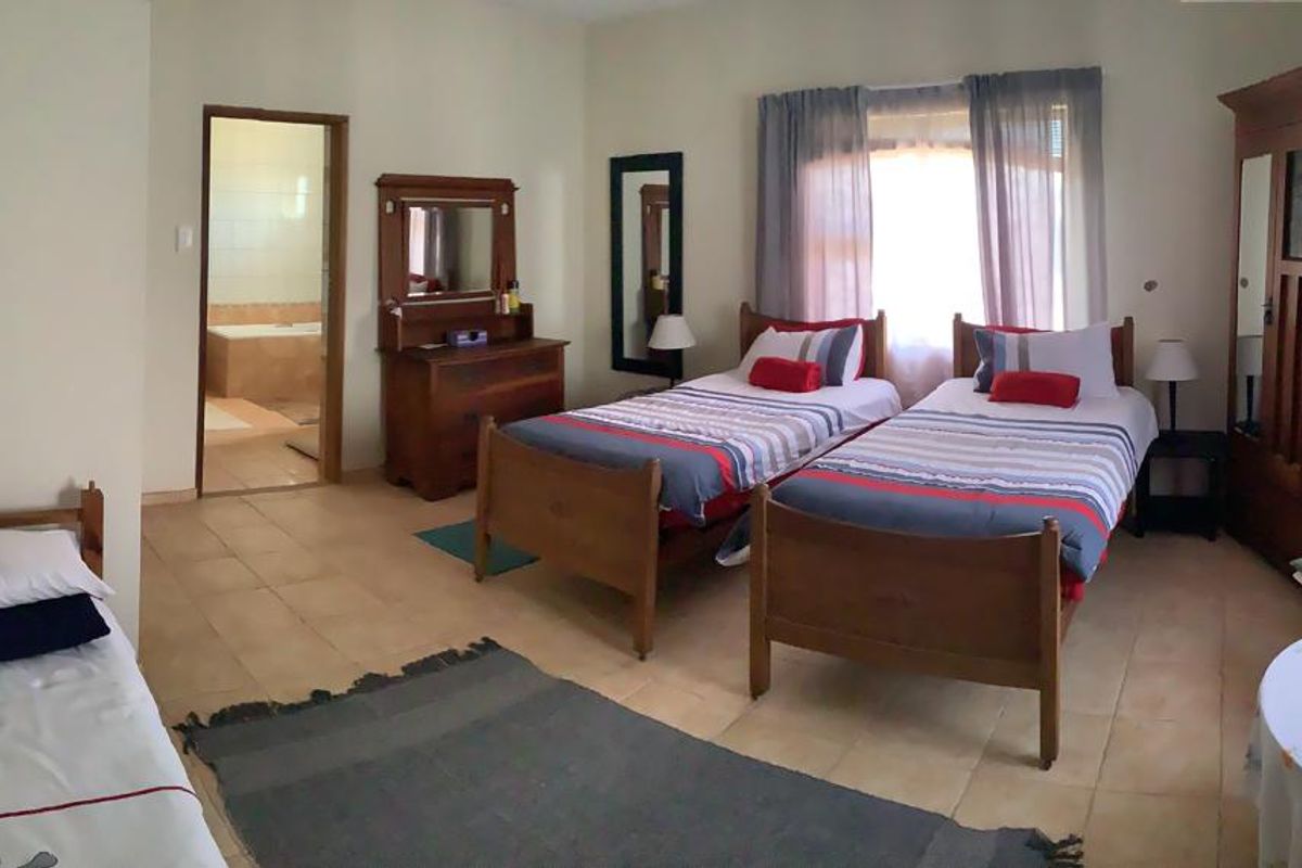 Spacious bedroom featuring tiled flooring, an en-suite bathroom, and large windows allowing for natural light.