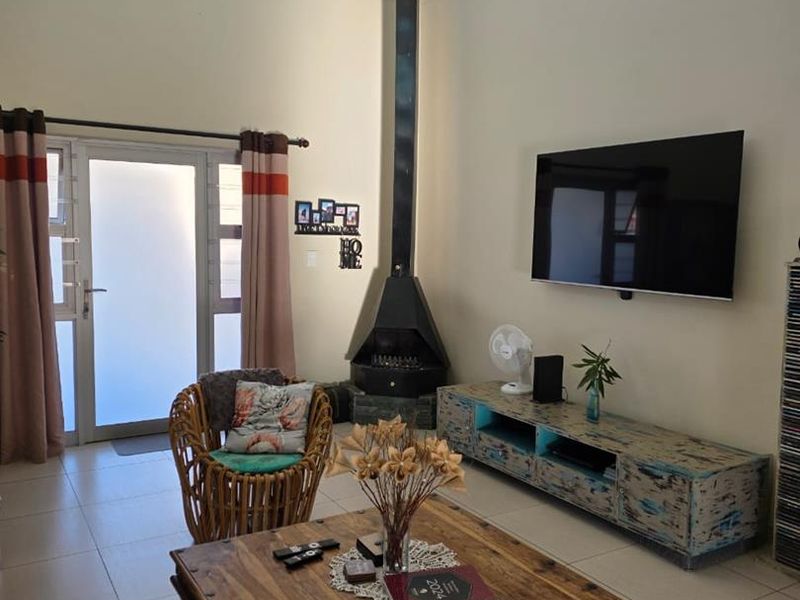Spacious living room featuring high vaulted ceilings, clerestory windows for natural light, tiled flooring, and a prominent black freestanding fireplace.