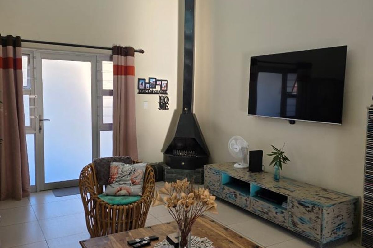 Spacious living room featuring high vaulted ceilings, clerestory windows for natural light, tiled flooring, and a prominent black freestanding fireplace.