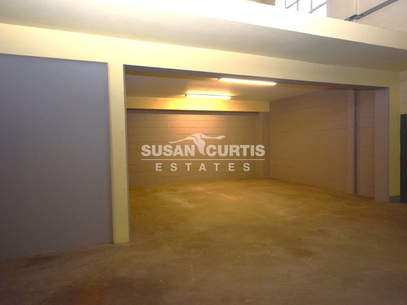 A spacious, empty industrial utility area featuring concrete flooring, exposed structural beams, and functional overhead fluorescent lighting.