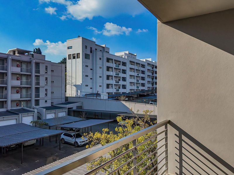 A view from a balcony overlooking the apartment complex parking area and surrounding residential buildings.