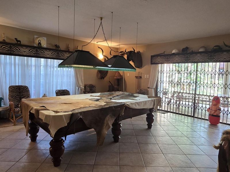 Spacious living area featuring tiled flooring, large sliding glass doors with security gates, and dual pendant lighting fixtures.