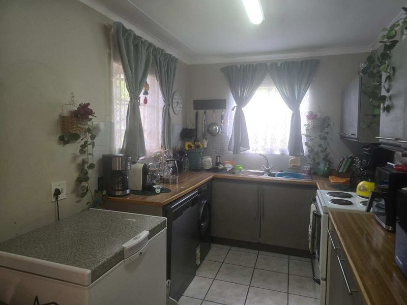 A functional kitchen featuring wooden countertops, built-in cabinetry, a double sink, and tiled flooring, offering a practical layout for daily meal preparation.