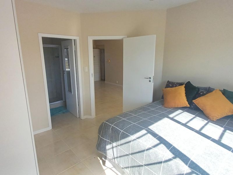 A bedroom featuring tiled flooring, a built-in wardrobe, and direct access to an en-suite bathroom.
