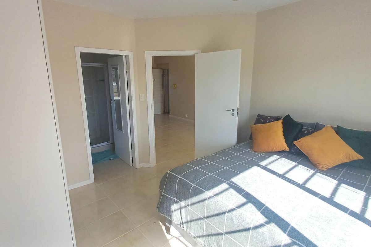 A bedroom featuring tiled flooring, a built-in wardrobe, and direct access to an en-suite bathroom.