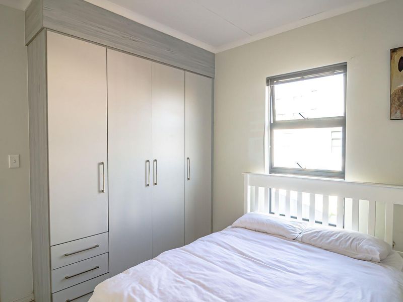 A well-maintained bedroom featuring a large built-in wardrobe with integrated drawers and a window providing natural light.