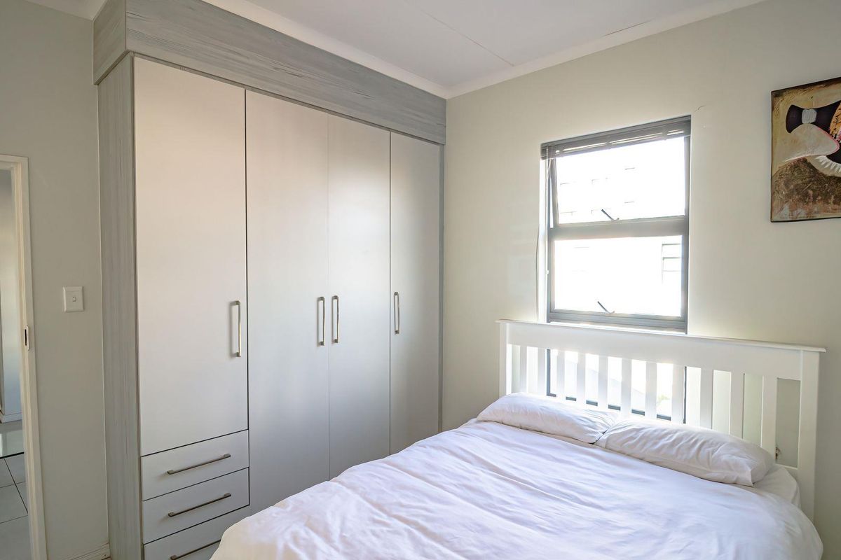 A well-maintained bedroom featuring a large built-in wardrobe with integrated drawers and a window providing natural light.
