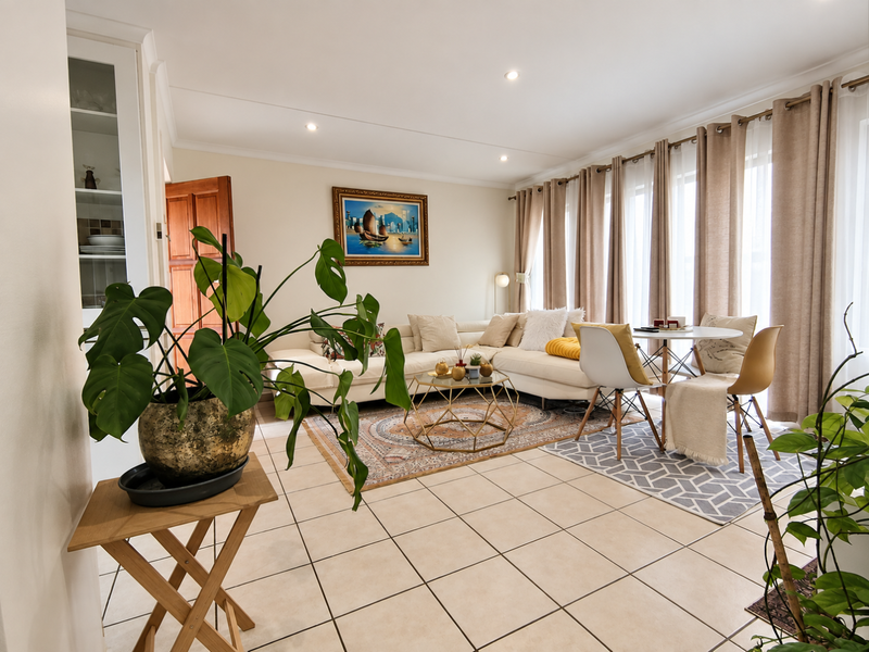 Bright open-plan living and dining area featuring neutral tiled flooring, recessed lighting, and large sliding glass doors providing ample natural light.