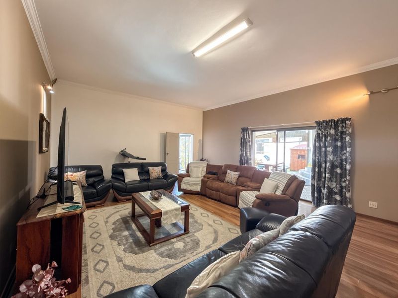 Spacious living room featuring laminate flooring, coving, and a large sliding glass door providing access to the outdoor area.