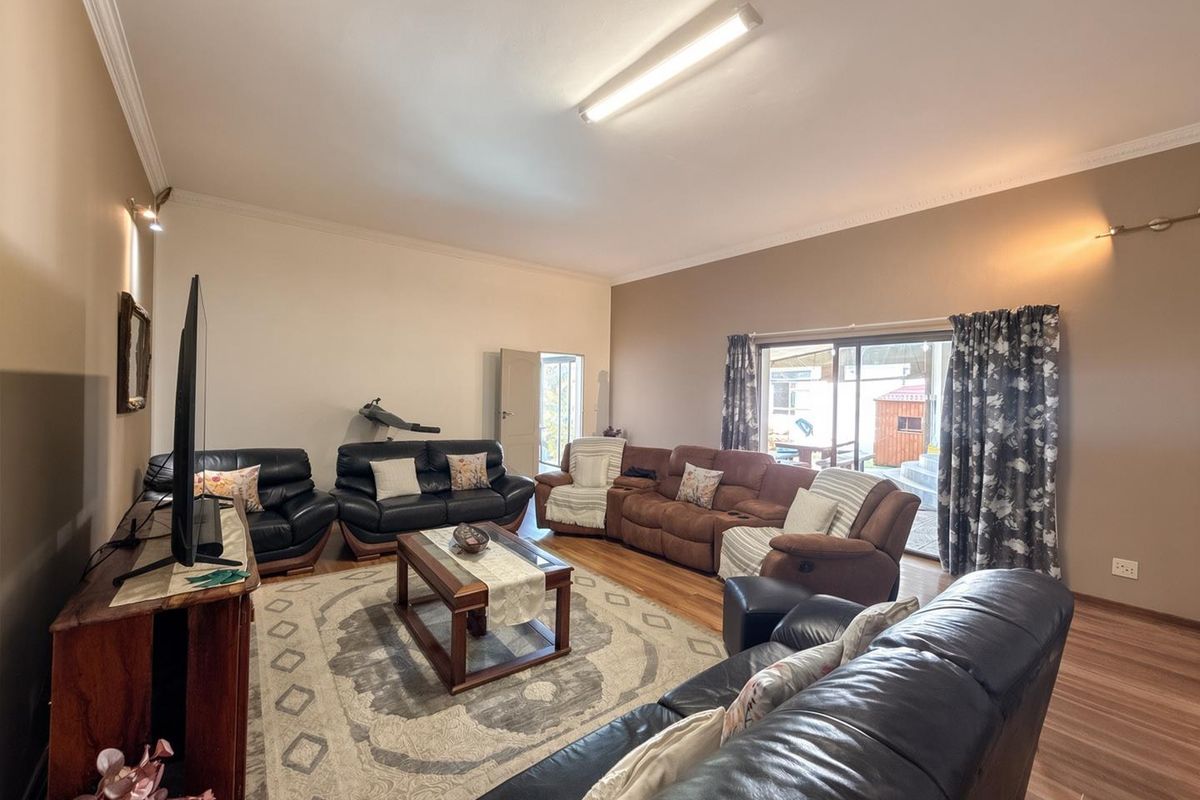 Spacious living room featuring laminate flooring, coving, and a large sliding glass door providing access to the outdoor area.