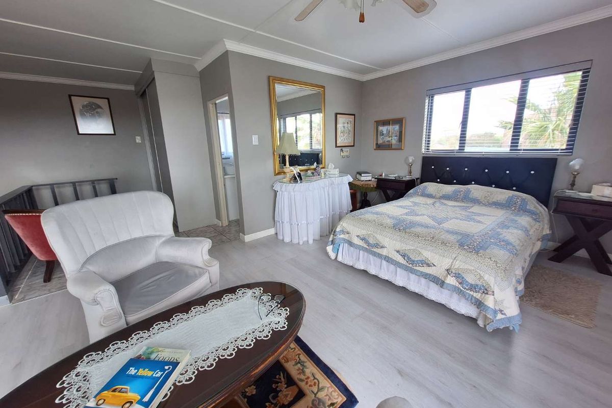 Spacious bedroom featuring light-toned laminate flooring, neutral wall finishes, and an en-suite bathroom access point.
