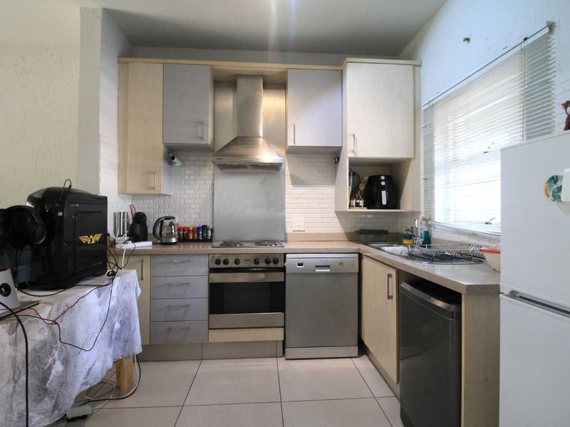 Functional kitchen featuring built-in cabinetry, stainless steel appliances, subway tile backsplash, and stone countertops with tiled flooring.
