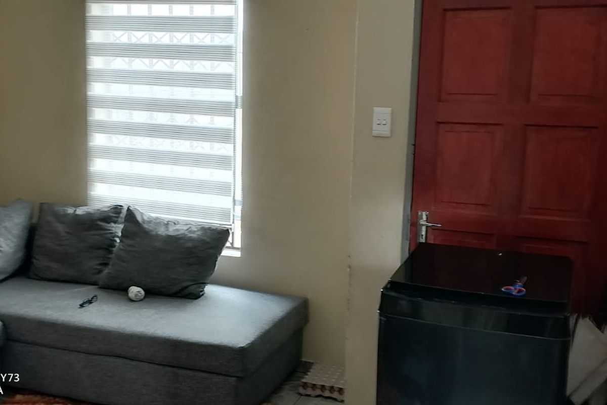 A living area featuring a window with fitted blinds and a solid timber door, providing a functional and compact space.